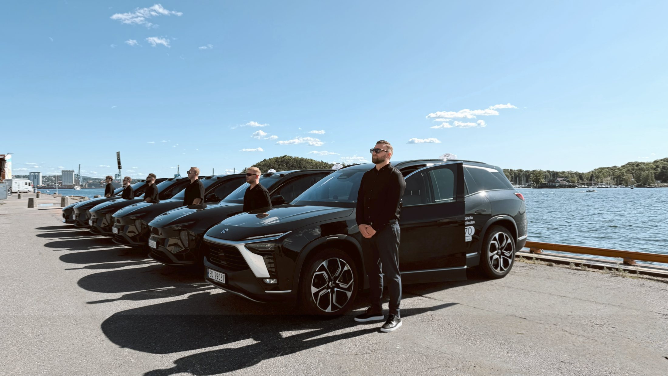 Sjåfør foran en rekke svarte NIO-biler fra Husby Taxi